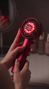 HairRevive tenu en main avec son bouton et sa tête de massage visibles